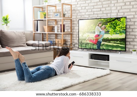 stock-photo-young-woman-lying-on-white-carpet-holding-remote-control-enjoying-watching-television-at-home-686338333.jpg