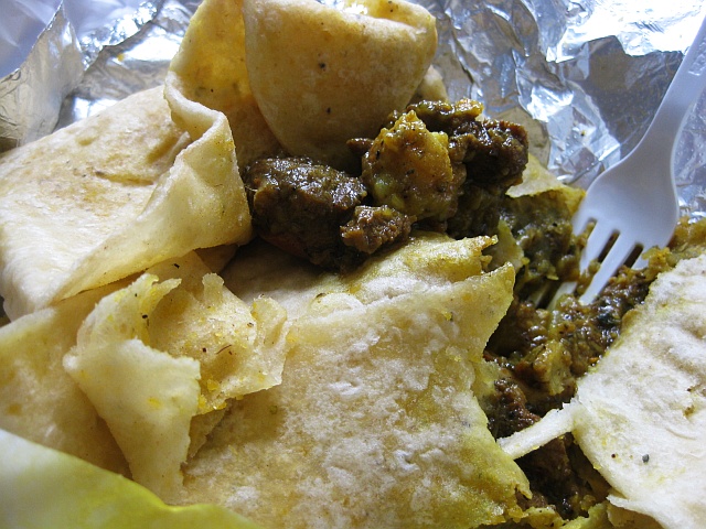 03-digging-into-the-roti-curry-goat-and-potatoes.jpg