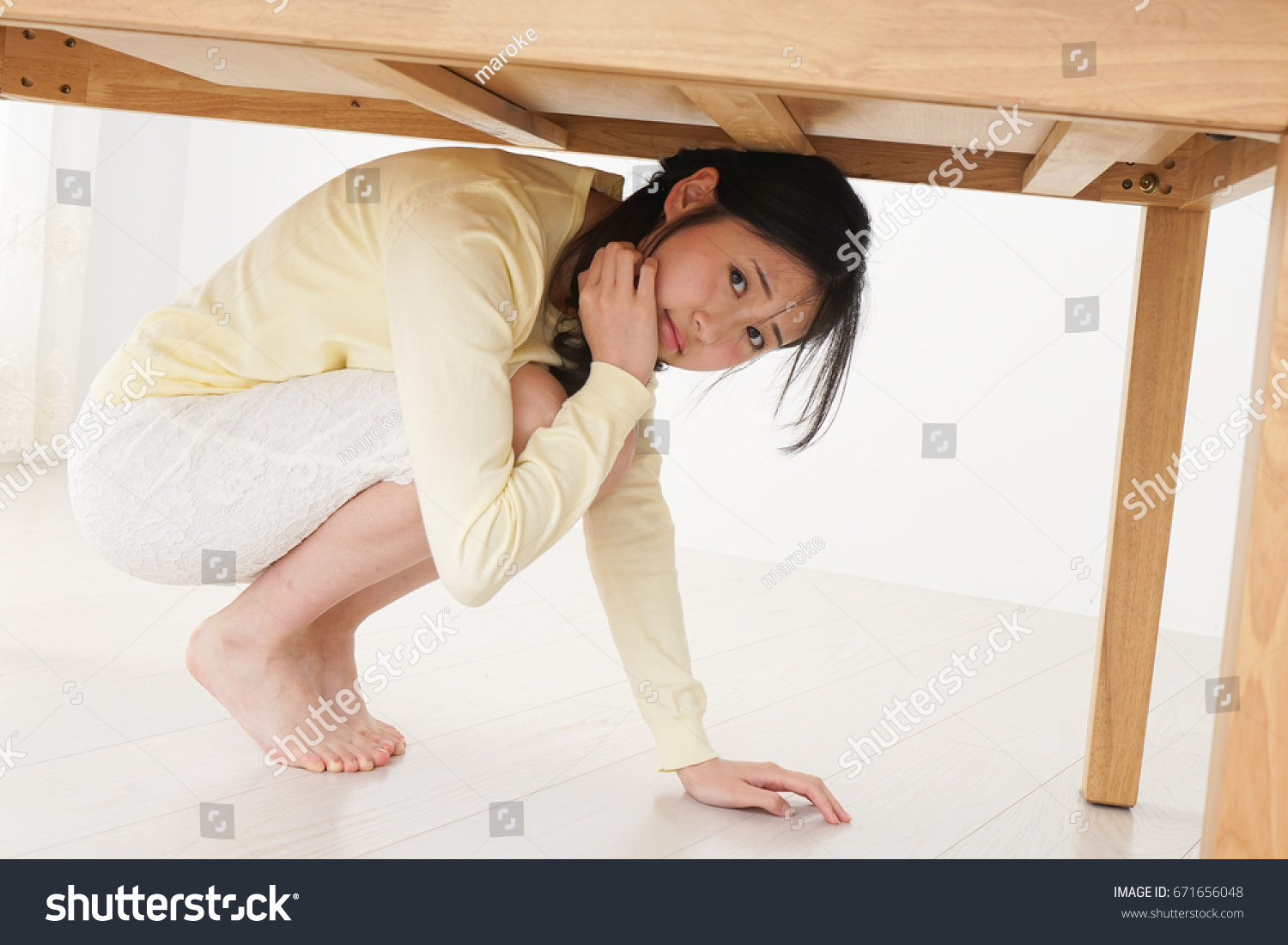 stock-photo-young-woman-hiding-under-table-from-earthquake-671656048.jpg